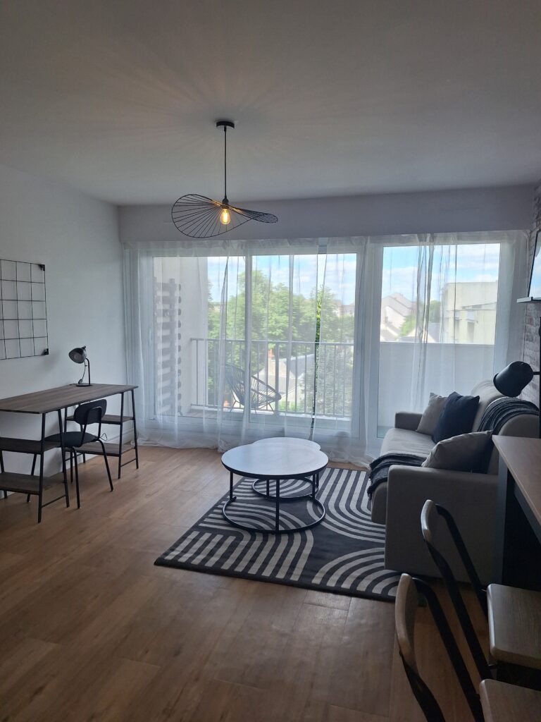 vue générale de la pièce avec coin séjour; bureau et balcon